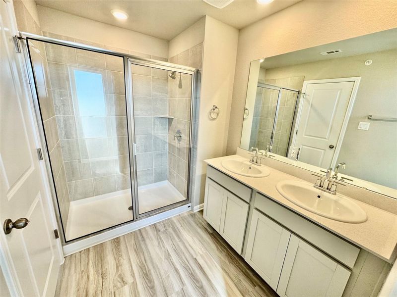 Full bath featuring a shower stall and light wood-style flooring