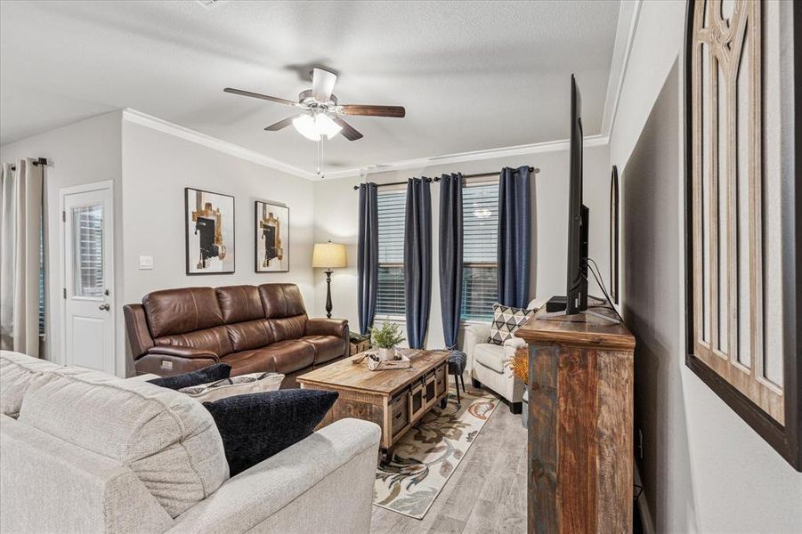 Living area with light wood-style flooring, ceiling fan, and crown molding Living area with light wood-style flooring, ceiling fan, and crown molding