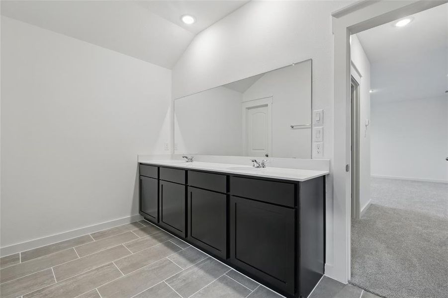 Full bathroom featuring double vanity and lofted ceiling