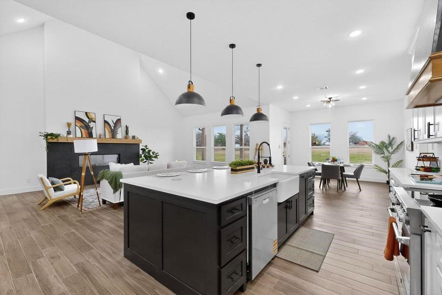 Kitchen featuring recessed lighting, dark cabinets, stainless steel appliances, open floor plan, and hanging light fixtures Kitchen featuring recessed lighting, dark cabinets, stainless steel appliances, open floor plan, and hanging light fixtures