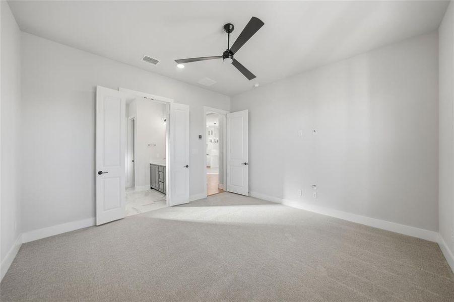 Unfurnished bedroom with light carpet, ensuite bathroom, and ceiling fan