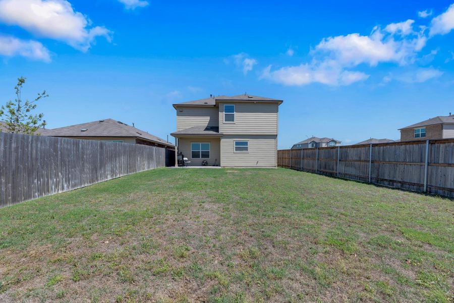 Back of house with a yard and a fenced backyard