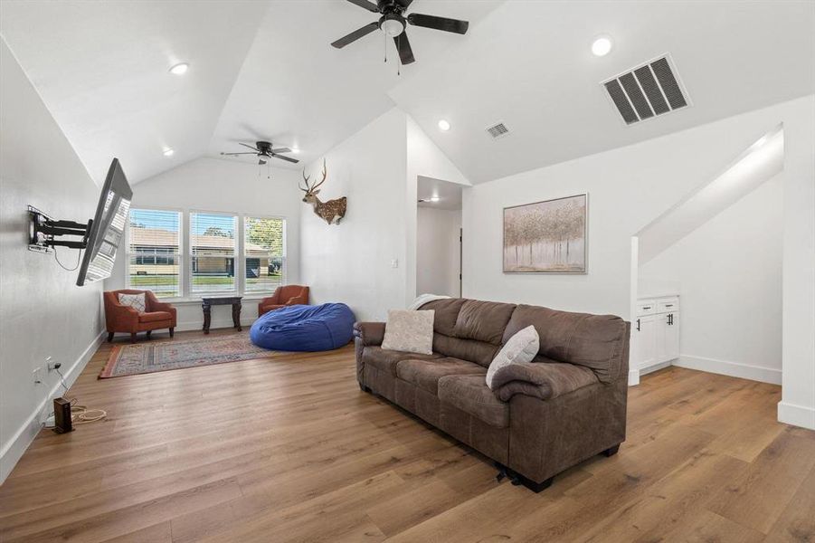 Living area with light wood-style floors, a ceiling fan, high vaulted ceiling, and recessed lighting