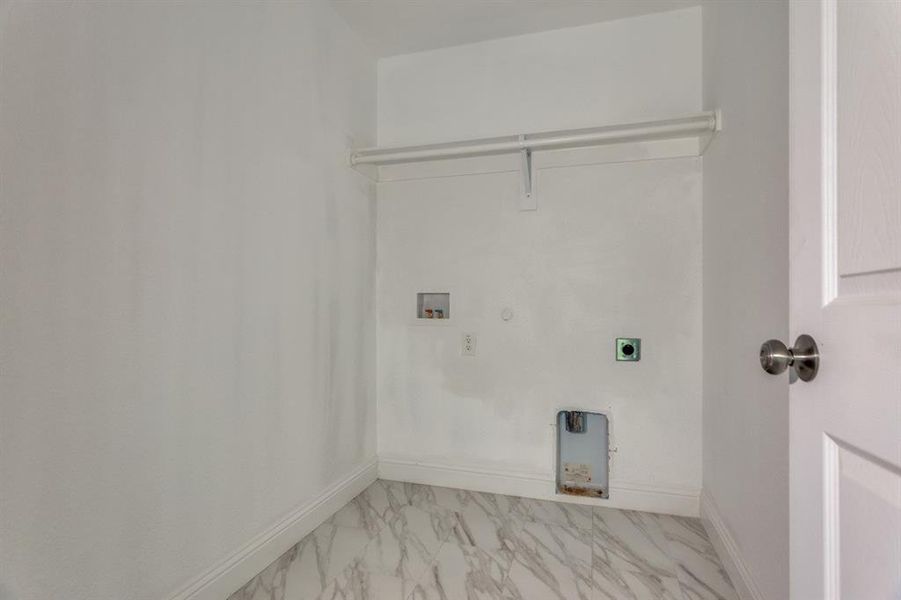 Laundry area with hookup for a gas dryer, electric dryer hookup, washer hookup, and light marble finish flooring