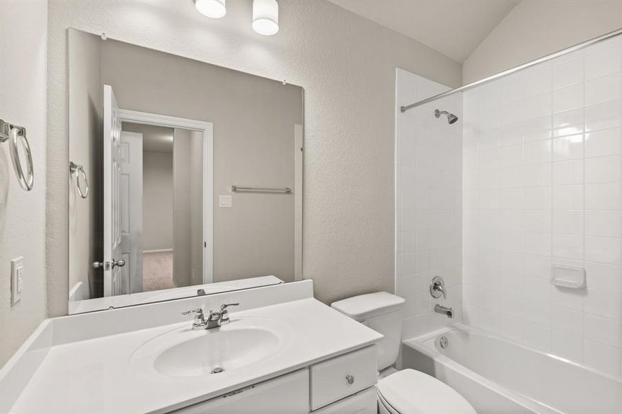 The secondary bath features tile flooring, white cabinetry and light countertops and a shower/tub combo. Perfect for accommodating any visiting family and friends.