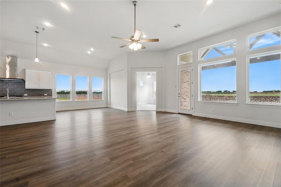 Unfurnished living room with ceiling fan, vaulted ceiling, dark wood finished floors, and visible vents