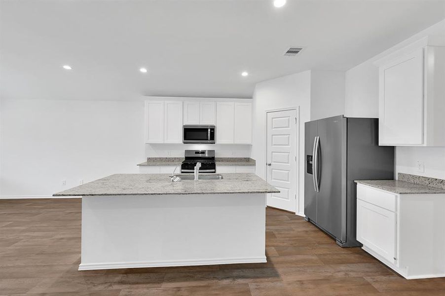 The beautiful cabinetry, center island, and backsplash serve as stunning design features—adding both elegance and visual appeal to the heart of the home.