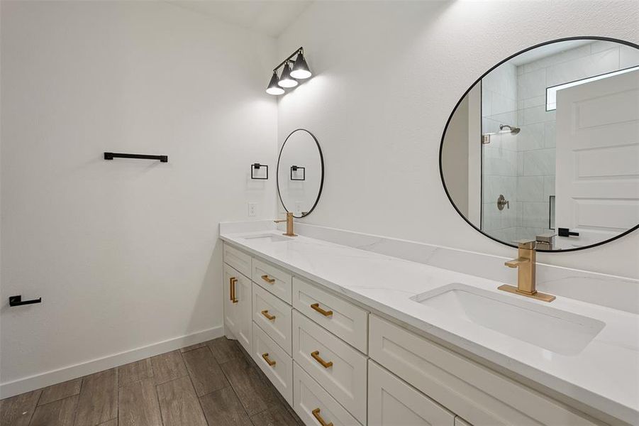 Double vanity featuring white cabinetry with gold-tone hardware, integrated undermount sinks, and white countertops