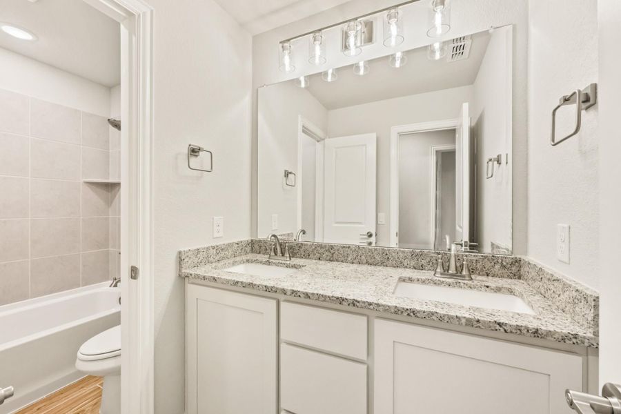 Bathroom with double sink vanity, granite countertop, white cabinets, and tiled shower-tub combo Bathroom with double sink vanity, granite countertop, white cabinets, and tiled shower-tub combo