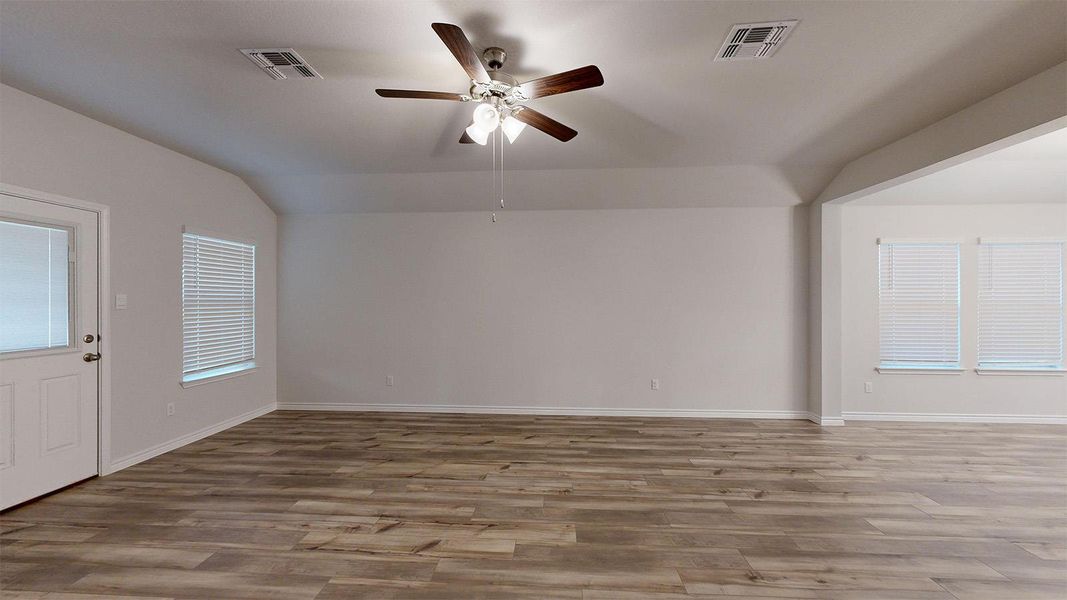 Unfurnished room featuring a ceiling fan, vaulted ceiling, and light wood-style floors