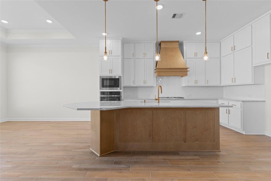 Another angle of the kitchen showcases the impressive island with generous seating, crisp white cabinetry with soft close doors and drawers, and a clean, bright design that feels both stylish and functional for the home chef.