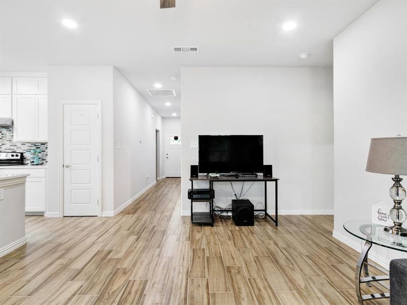 Open-concept living space featuring wood-finish flooring, recessed lighting, and a neutral color palette