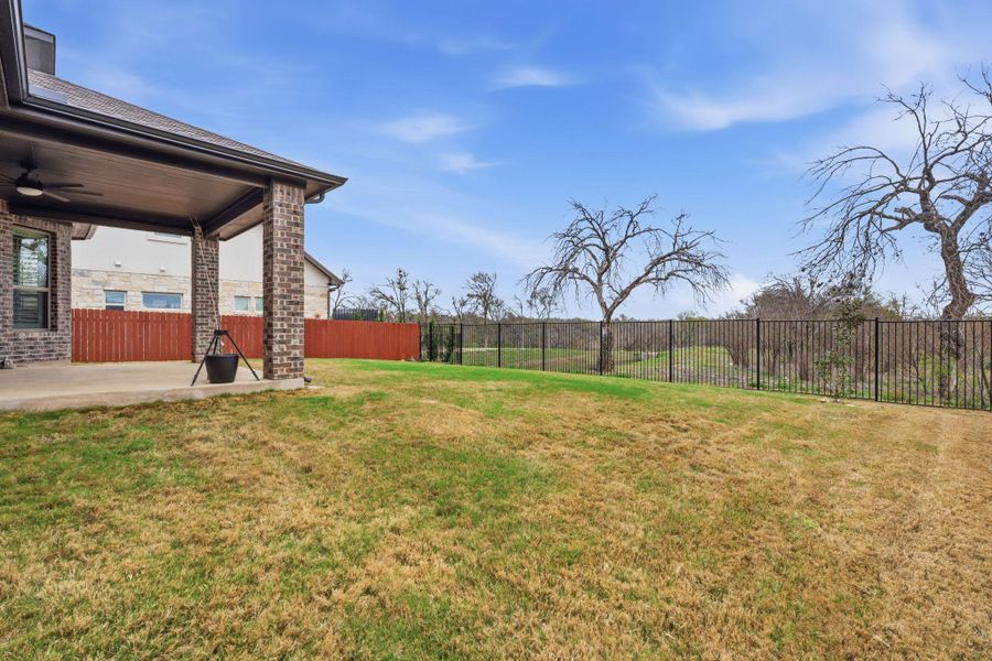 Fenced backyard with ceiling fan and a patio area