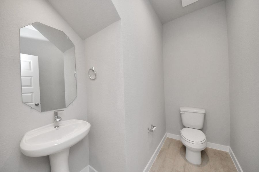 This half bathroom features a stylish pedestal sink, modern hardware, and bright recessed lighting, creating a sleek and inviting space. Sample photo of completed home with similar floor plan. Actual colors and selections may vary. This half bathroom features a stylish pedestal sink, modern hardware, and bright recessed lighting, creating a sleek and inviting space. Sample photo of completed home with similar floor plan. Actual colors and selections may vary.