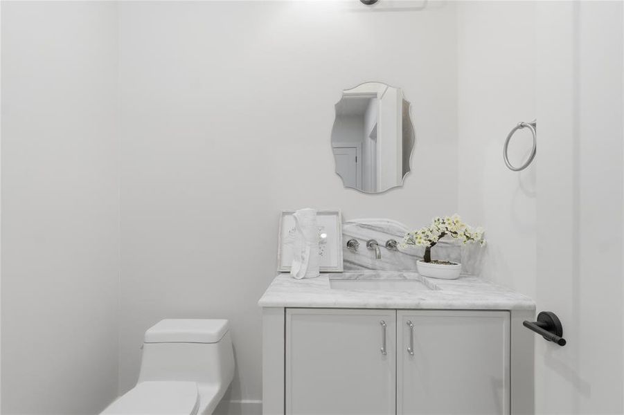 Powder bath with marble vanity, wall-mount faucet, and designer mirror Powder bath with marble vanity, wall-mount faucet, and designer mirror