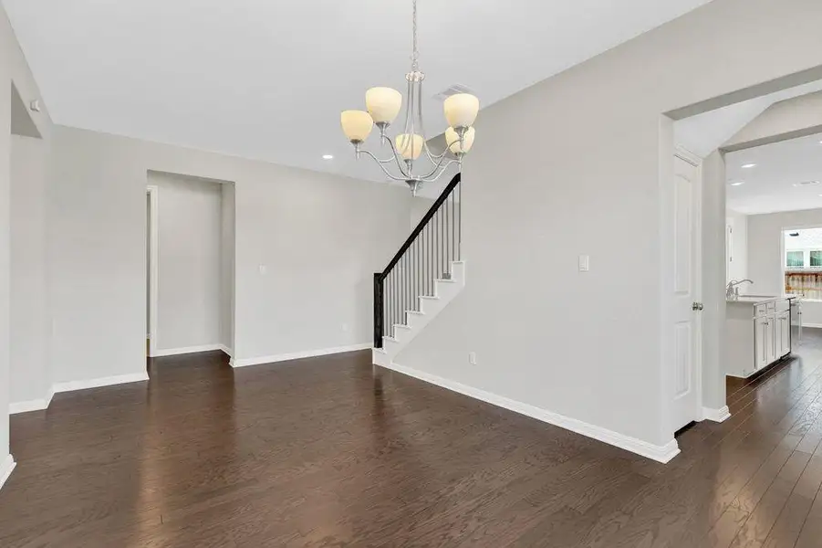 Unfurnished living room featuring dark wood-style floors, a chandelier, recessed lighting, and stairs Unfurnished living room featuring dark wood-style floors, a chandelier, recessed lighting, and stairs