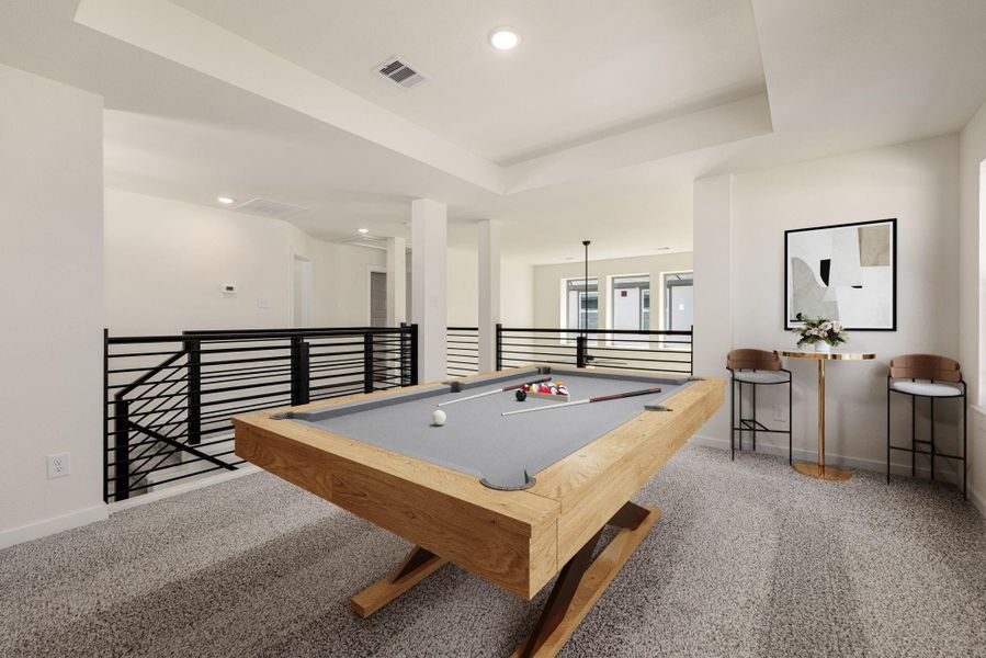 This spacious upstairs Game Room offers a dedicated entertainment hub, overlooking the floor below via a stylish black horizontal metal railing. The room is brightly lit with overhead recessed lighting and features soft, neutral-toned carpeting throughout. *Virtually Staged This spacious upstairs Game Room offers a dedicated entertainment hub, overlooking the floor below via a stylish black horizontal metal railing. The room is brightly lit with overhead recessed lighting and features soft, neutral-toned carpeting throughout. *Virtually Staged