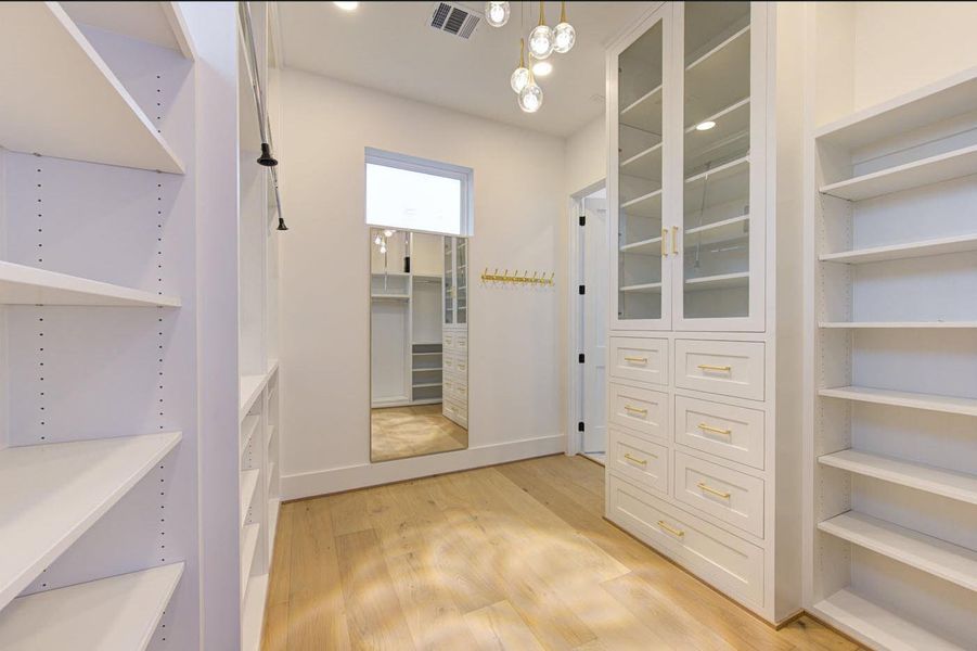 Her private closet features a sparkling chandelier, pull-down racks, and glass-enclosed cabinetry.