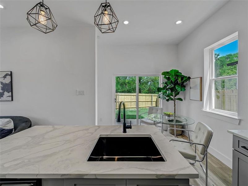 Kitchen featuring sink, plenty of natural light, light stone counters, and hardwood / wood-style floors