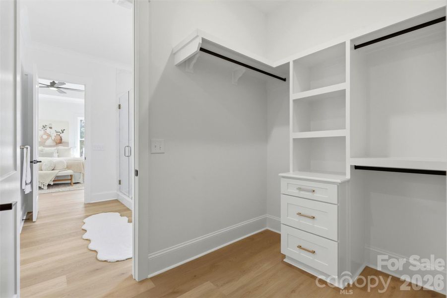 his & hers custom WIC closet w/ wooden shelves connected to..