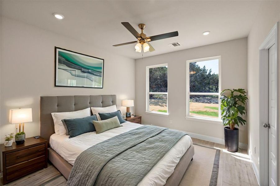 Bedroom with multiple windows, hardwood / wood-style floors, and ceiling fan