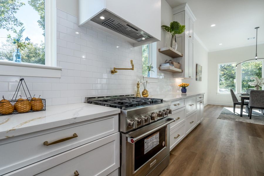 Modern kitchen with gas range, pot filler, and sleek white cabinetry. Modern kitchen with gas range, pot filler, and sleek white cabinetry.