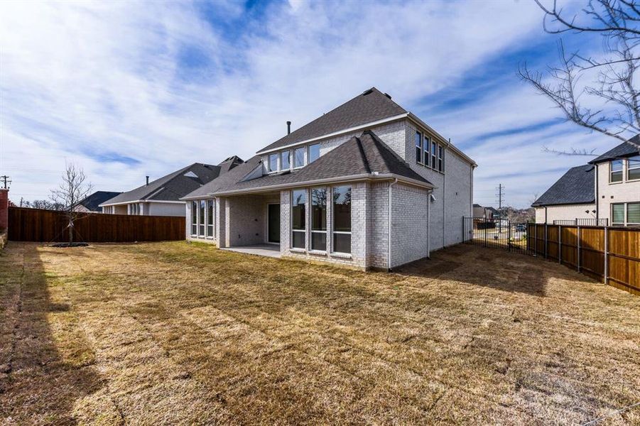 Back of house featuring a patio area, brick siding, a fenced backyard, and roof with shingles