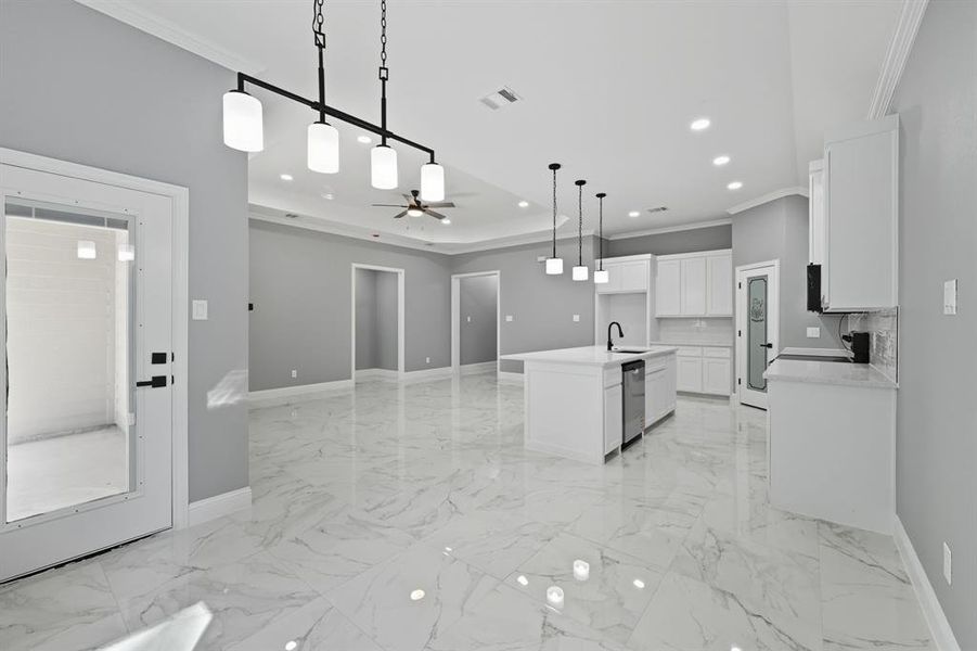 Kitchen featuring ornamental molding, open floor plan, decorative light fixtures, white cabinets, and recessed lighting Kitchen featuring ornamental molding, open floor plan, decorative light fixtures, white cabinets, and recessed lighting