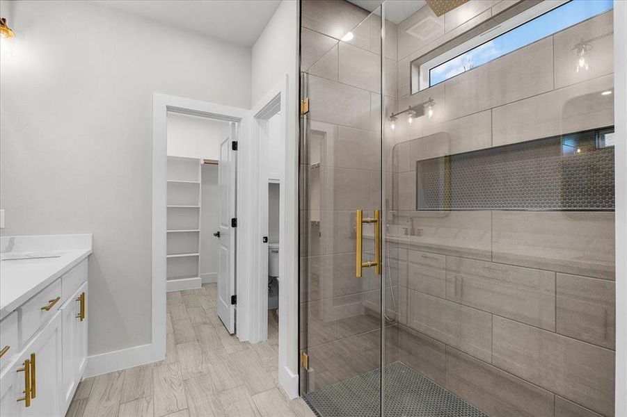 Bathroom with baseboards, a shower stall, vanity, and a spacious closet