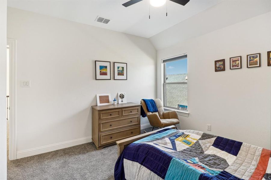 Bedroom with light colored carpet, visible vents, ceiling fan, baseboards, and vaulted ceiling Bedroom with light colored carpet, visible vents, ceiling fan, baseboards, and vaulted ceiling