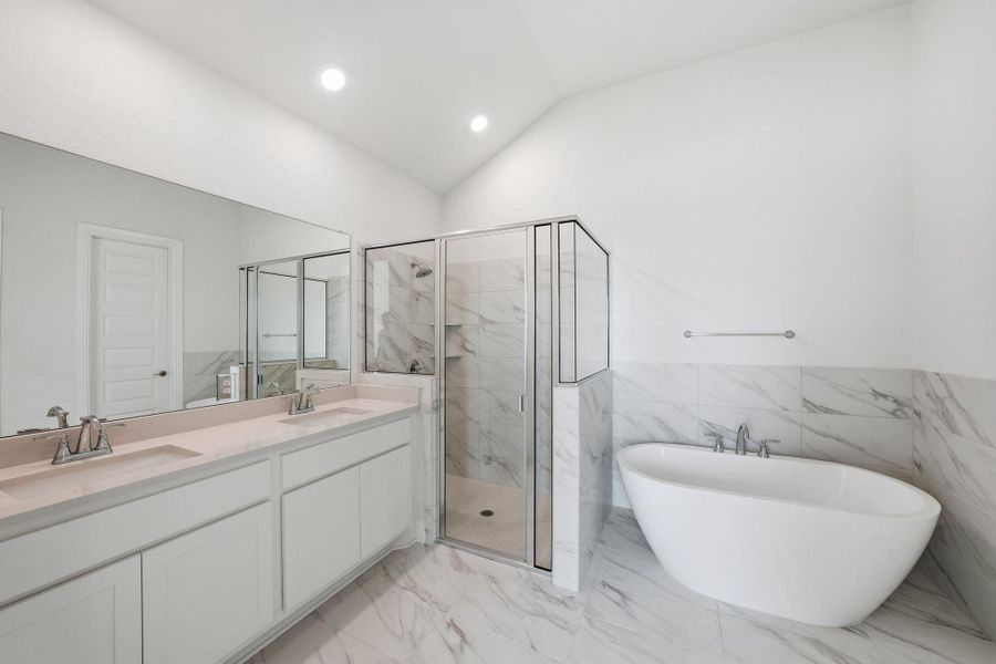 Bathroom featuring a marble finish shower, double vanity, a freestanding bath, tile walls, and recessed lighting Bathroom featuring a marble finish shower, double vanity, a freestanding bath, tile walls, and recessed lighting
