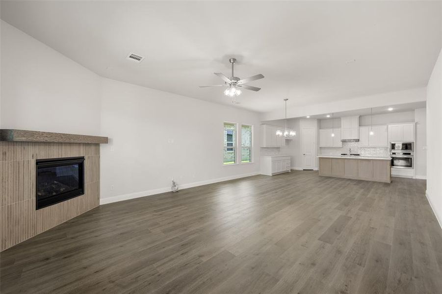 Unfurnished living room with a fireplace, ceiling fan, a chandelier, recessed lighting, and wood finished floors Unfurnished living room with a fireplace, ceiling fan, a chandelier, recessed lighting, and wood finished floors