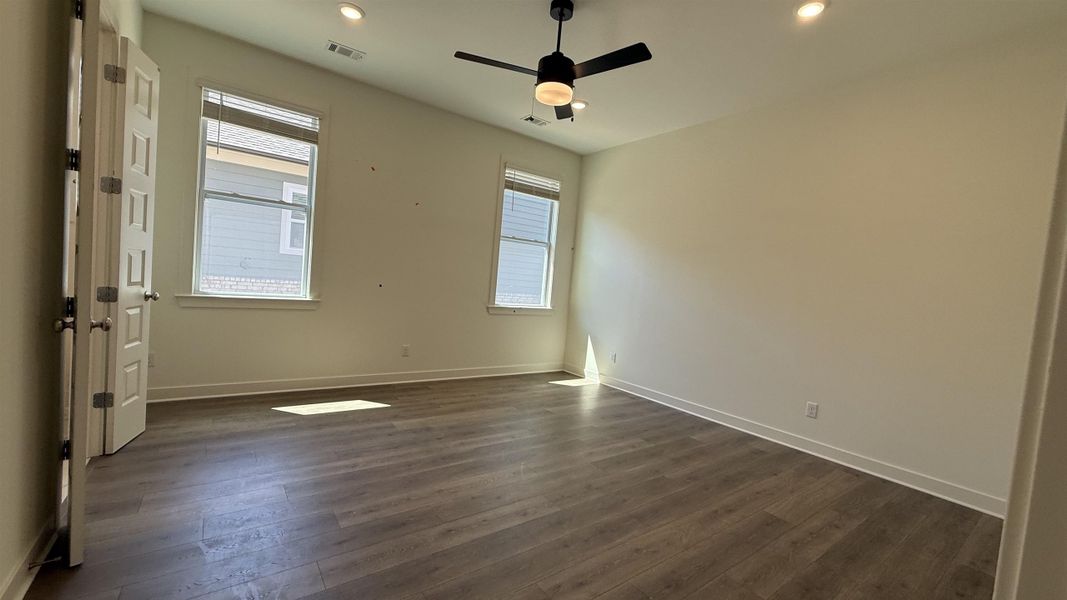 Empty room with dark wood-type flooring, ceiling fan, and recessed lighting