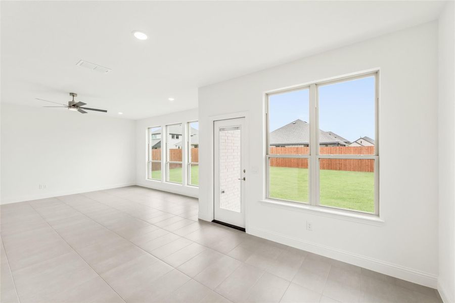Open living area with tile floors, ceiling fan, and back door with large windows overlooking fenced yard Open living area with tile floors, ceiling fan, and back door with large windows overlooking fenced yard