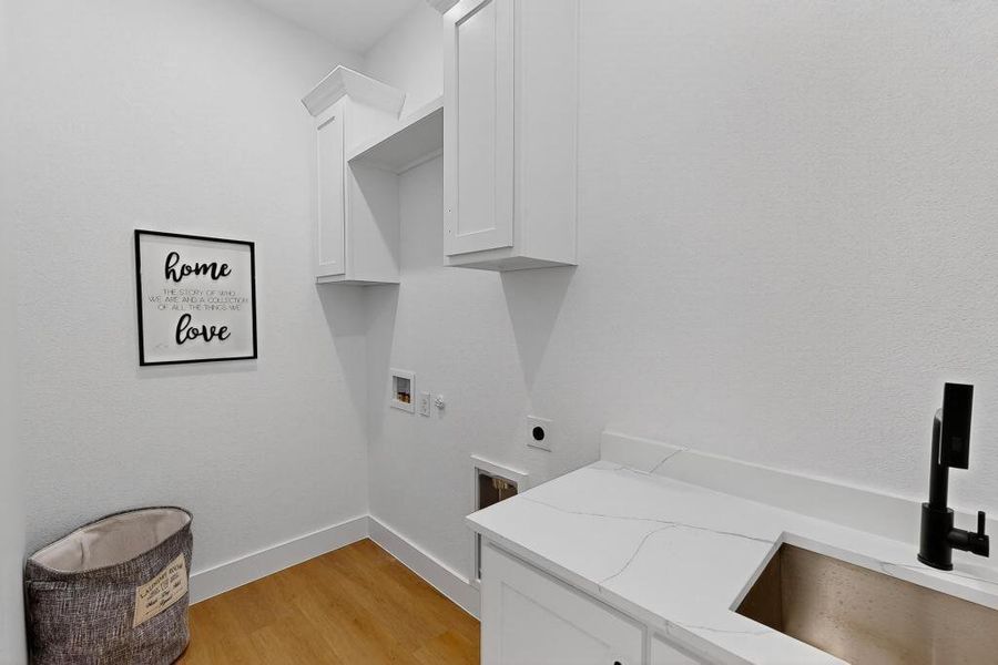 Washroom with cabinet space, hookup for an electric dryer, washer hookup, and light wood-style floors