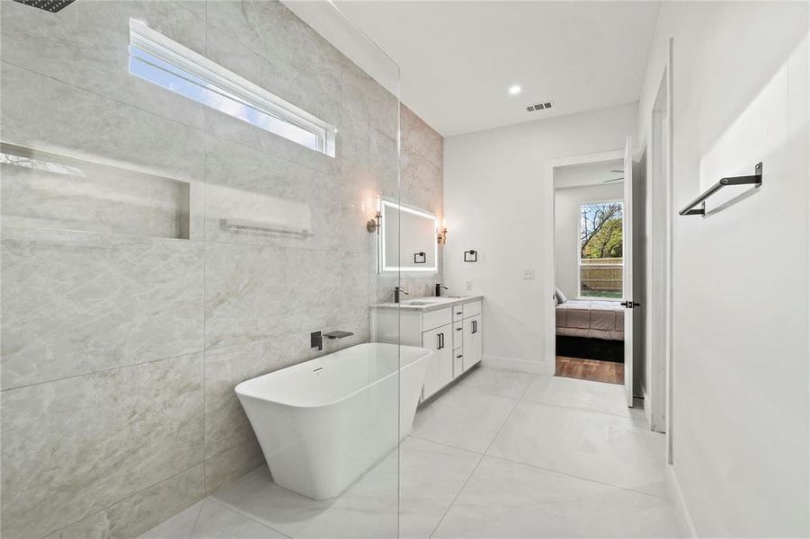 Full bath featuring tile walls, vanity, ensuite bathroom, a freestanding tub, and recessed lighting
