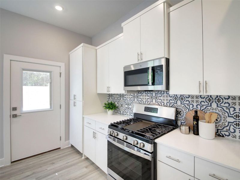 Kitchen featuring stainless steel appliances, white cabinetry, light wood-type flooring, decorative backsplash, and recessed lighting