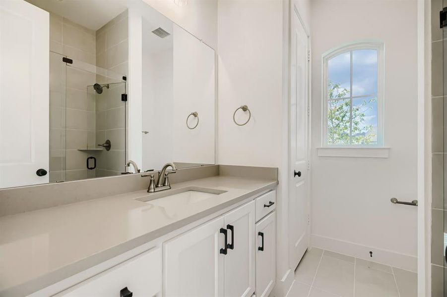 Vanity with a single undermount sink, a wide rectangular mirror, and white shaker-style cabinetry with matte black hardware Vanity with a single undermount sink, a wide rectangular mirror, and white shaker-style cabinetry with matte black hardware