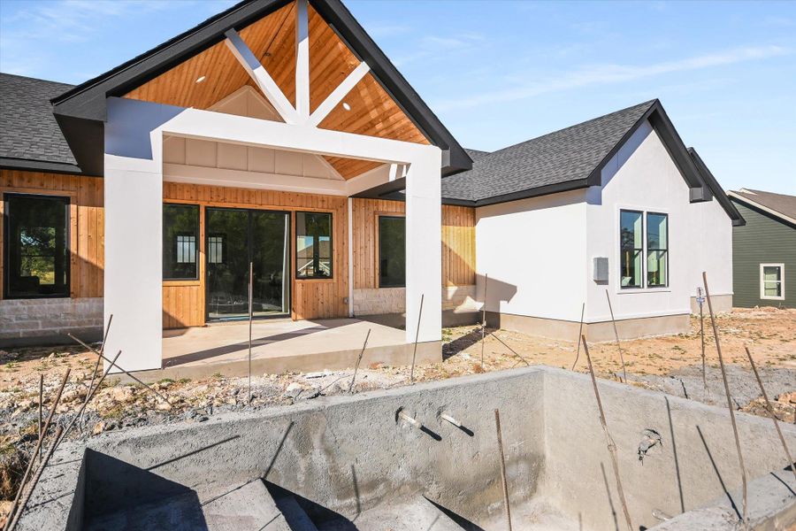 Rear view of property with a shingled roof and a patio area
