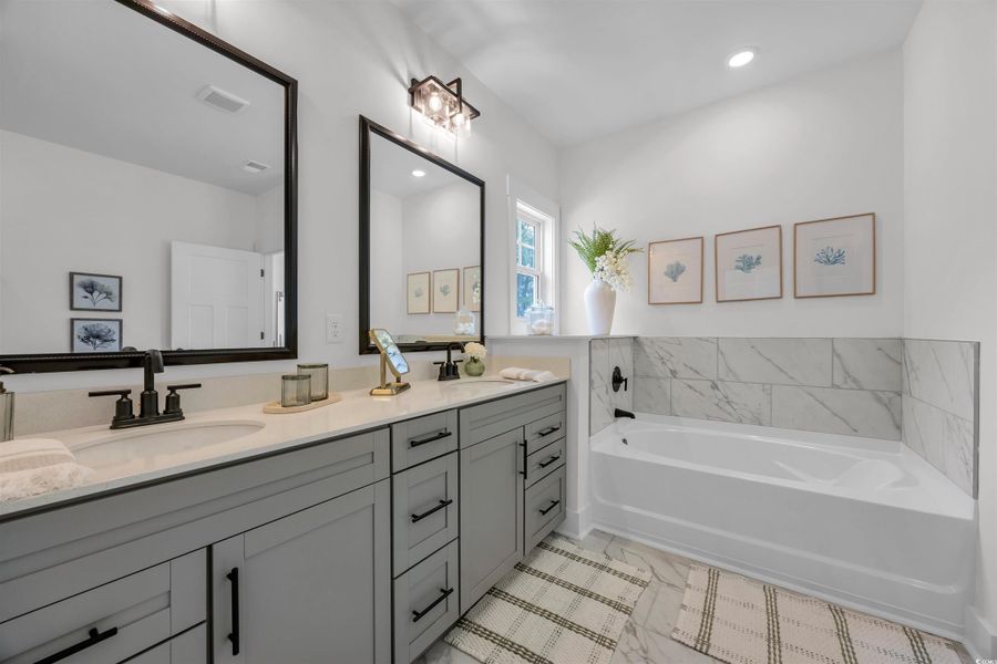 Bathroom featuring double vanity, a bath, and recessed lighting