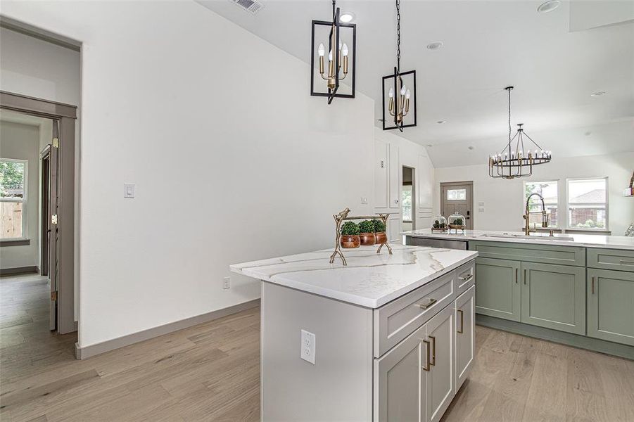 Kitchen featuring a chandelier, a kitchen island, lofted ceiling, light wood finished floors, and green cabinetry