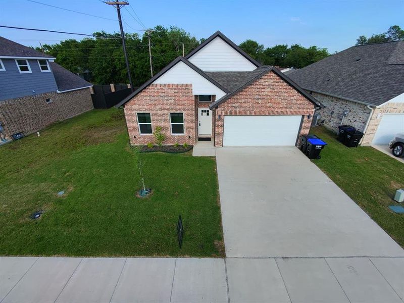 View of front facade with brick siding, driveway, an attached garage, and a front yard View of front facade with brick siding, driveway, an attached garage, and a front yard