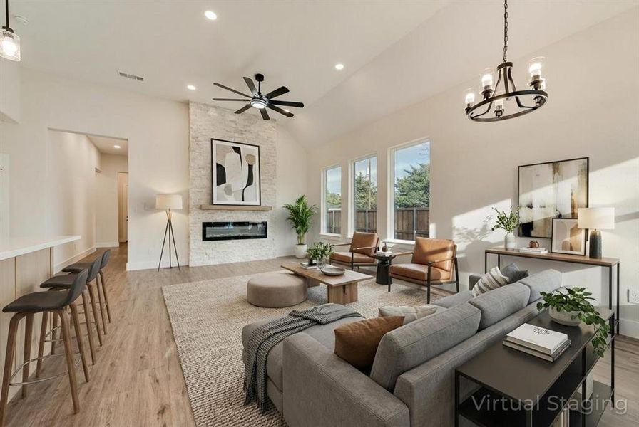 Virtually Staged Living room with a fireplace, light wood-style flooring, vaulted ceiling, recessed lighting, and a chandelier