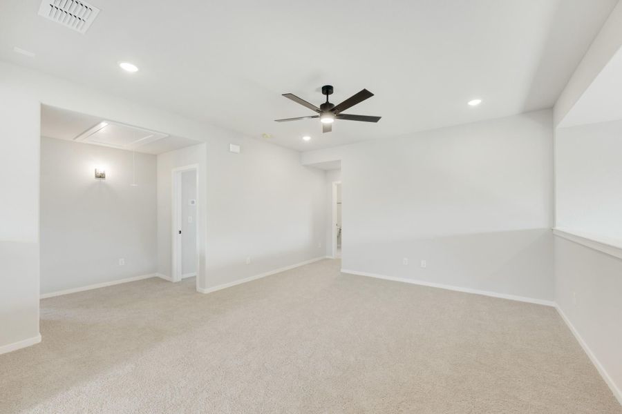 Empty bedroom with beige carpet, white walls, ceiling fan, and recessed lighting