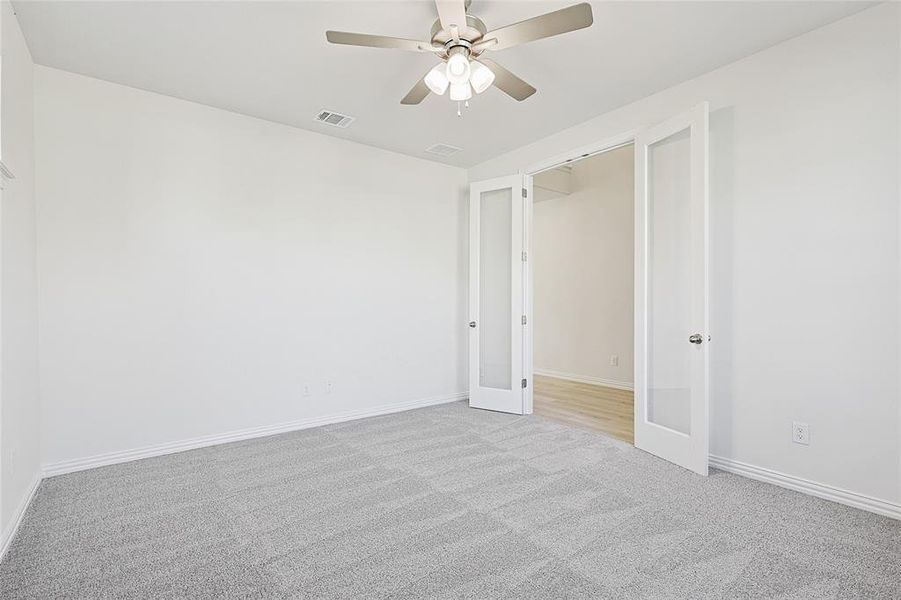 Empty room with french doors, light colored carpet, and ceiling fan