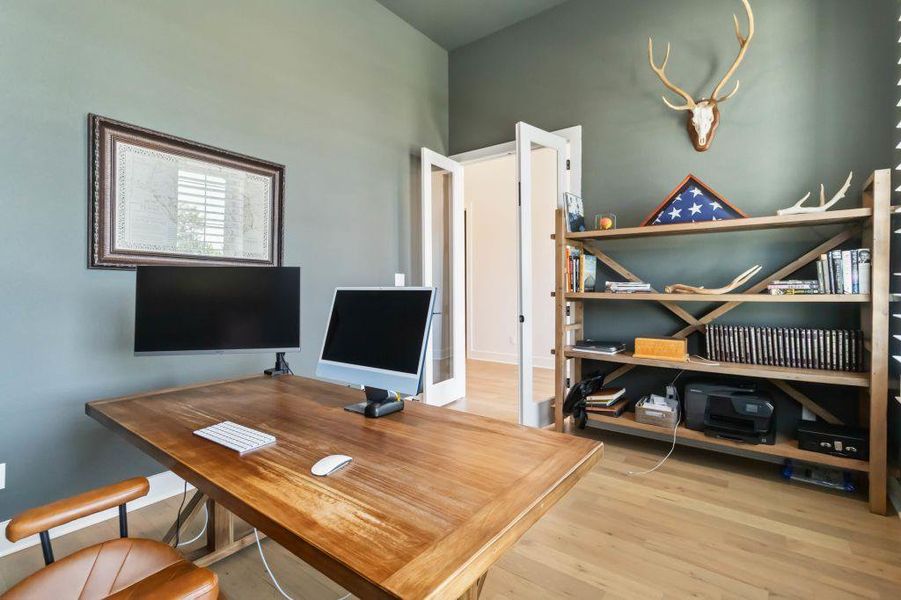 A dedicated home office provides a functional workspace with a large wooden desk and hardwood flooring.