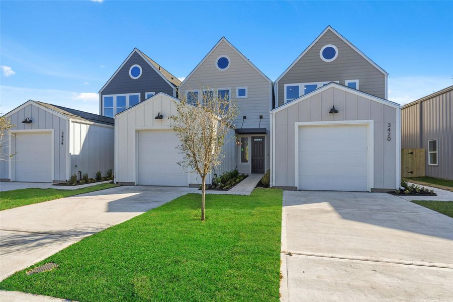 Modern house with a sleek, geometric design featuring one single-car garage and a clean, minimalist facade. The property has a small, well-maintained front lawn and a paved driveway.