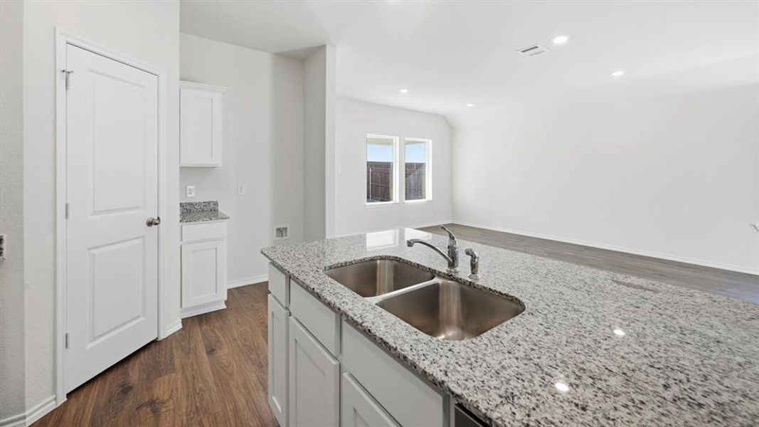 Kitchen with dark wood-style floors, white cabinets, light stone counters, and recessed lighting Kitchen with dark wood-style floors, white cabinets, light stone counters, and recessed lighting