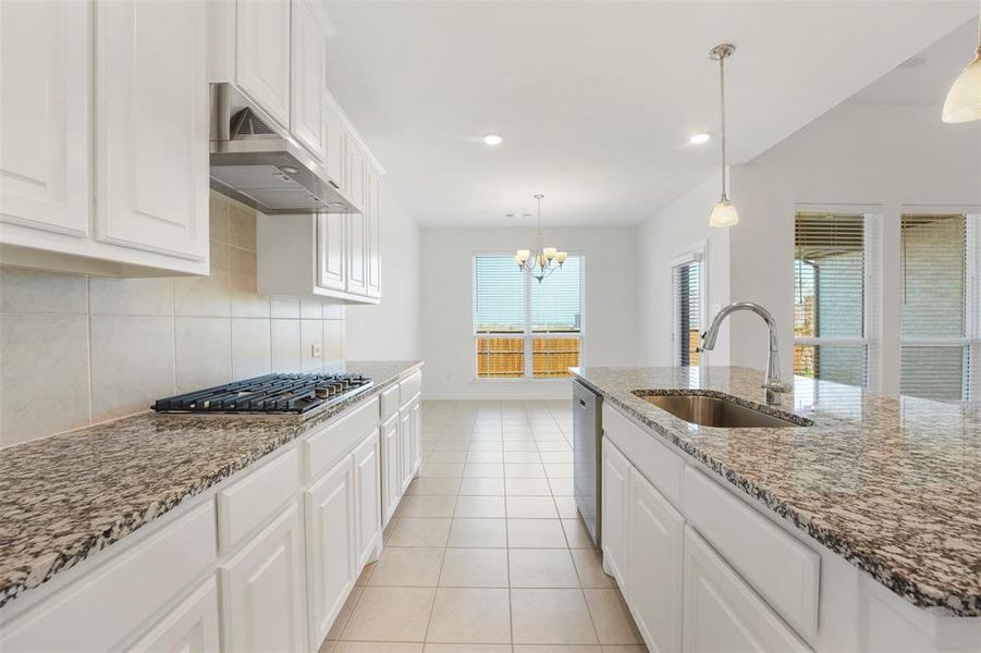 Kitchen featuring light stone countertops, stainless steel appliances, sink, extractor fan, and white cabinetry