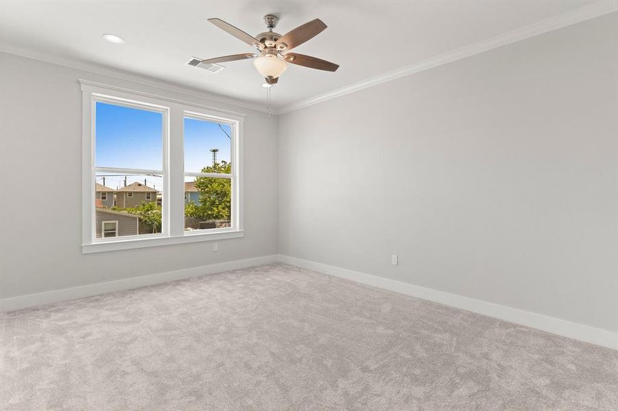 This is a bright, Primary room featuring plush carpeting, a ceiling fan, and a large double window offering plenty of natural light.